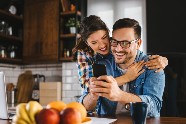 Two people using smartphone in kitchen at home